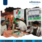 Community health fair scene: volunteers at a table with medical supplies, banners for MOXIEHEAL Foundation behind them.